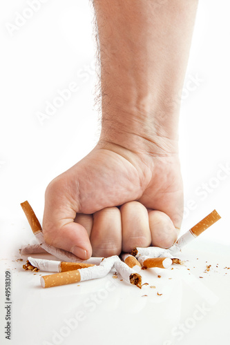 Human fist breaking cigarettes on white background