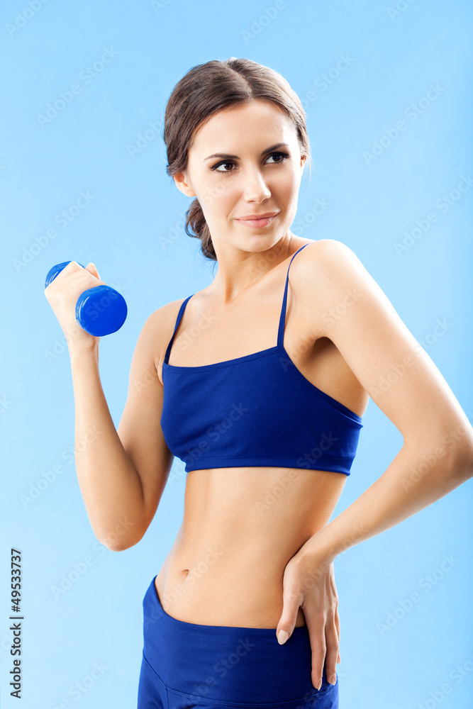 Woman in fitness wear with dumbbell, over blue Woman in fitness wear with dumbbell, over blue