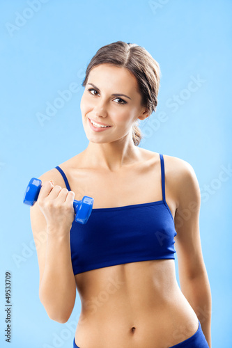 Woman in fitness wear with dumbbell, over blue