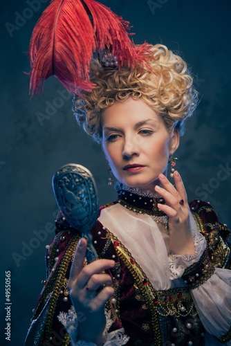 Haughty queen in royal dress with mirror