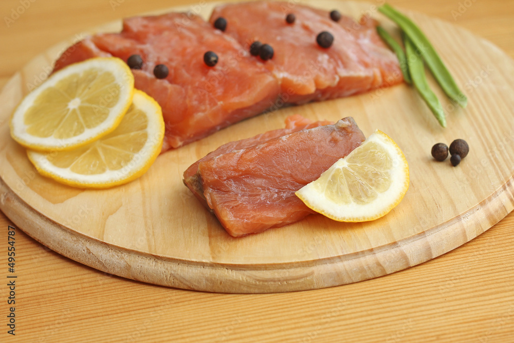 salmon fillet with lemon and spices on wooden board, close-up salmon fillet with lemon and spices on wooden board, close-up