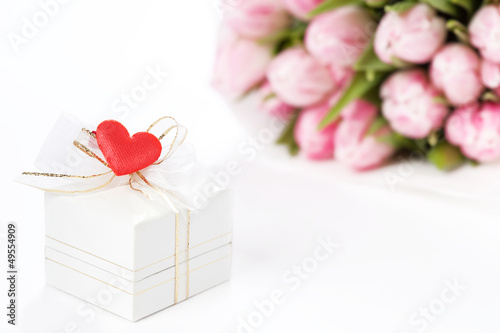 Gift box decorated with heart with tulips on the background