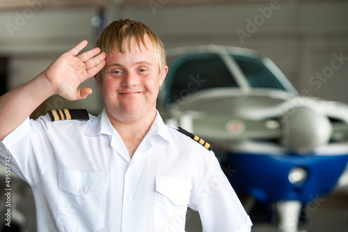 Portrait of young pilot with down syndrome in hangar. photo