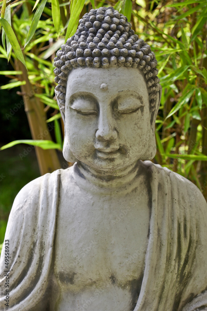 Buddha sculpture with bamboo leaves in background