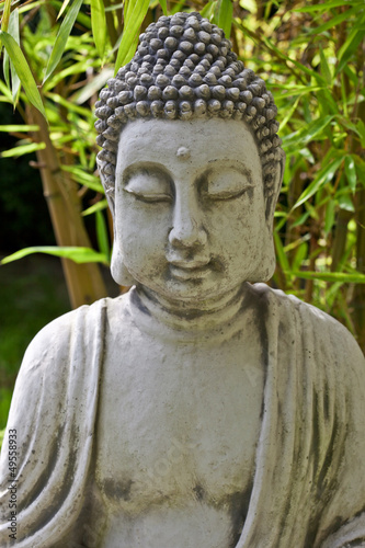 Buddha sculpture with bamboo leaves in background