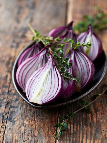 Halved red onions with thyme on a ceramic plate