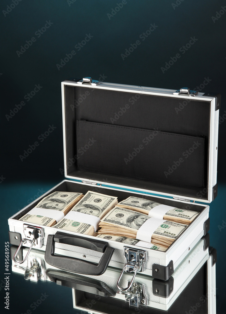 Suitcase with 100 dollar bills on dark color background Suitcase with 100 dollar bills on dark color background