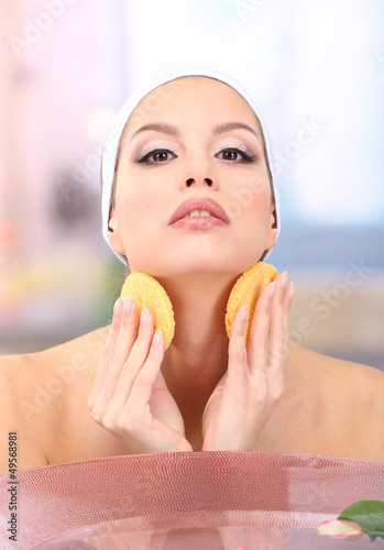 Young woman washing her fac...