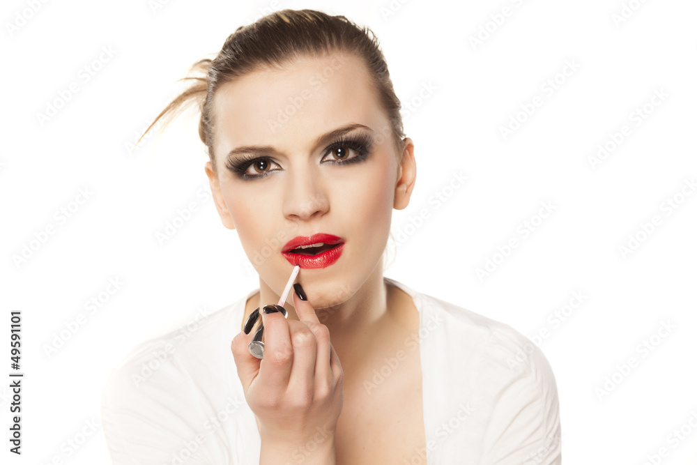 beautiful girl with bright makeup puts lip gloss beautiful girl with bright makeup puts lip gloss