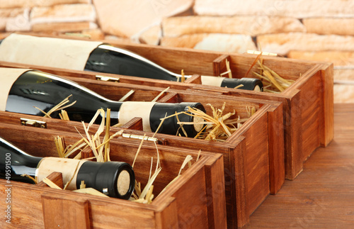 Bottles of old red wine in gift wooden box, on stone background