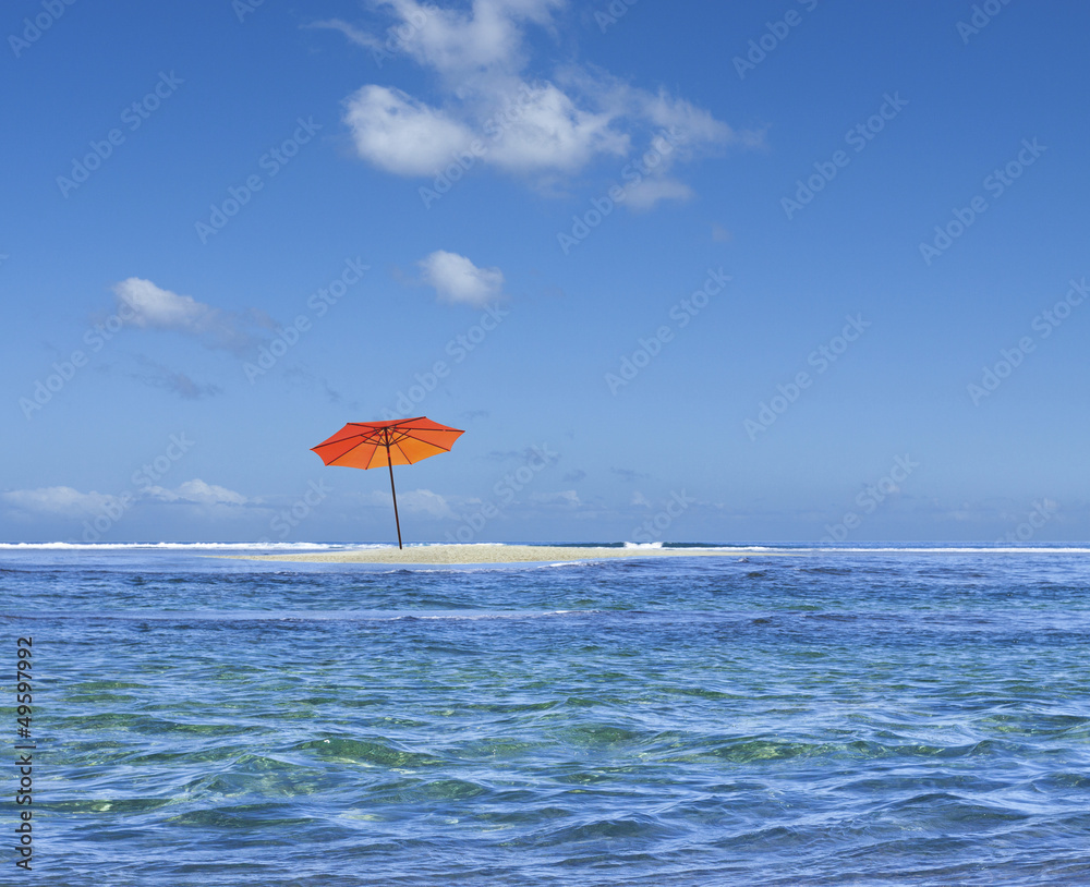 parasol de plage sur îlot de sable blanc
