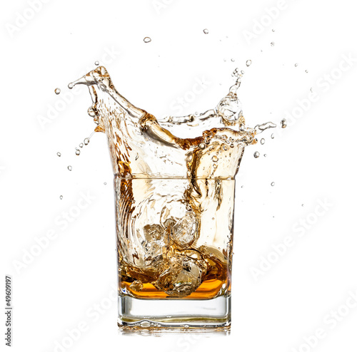 Whiskey splashing out of glass, isolated on white background