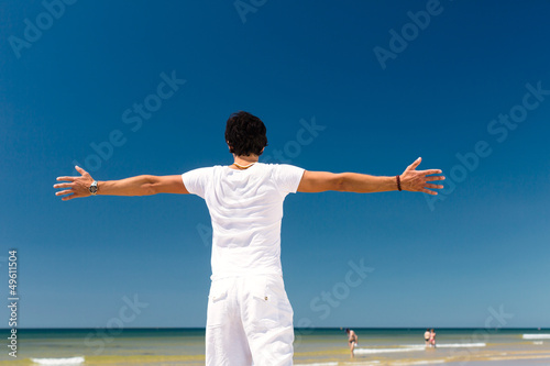 Handsome man standing in the sun on beach