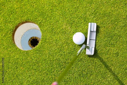 Fotografie Golf player putting ball in hole