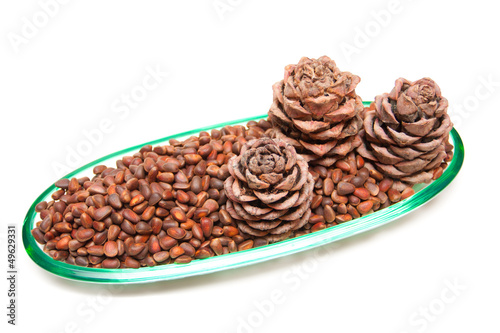 Three pine cones and pine nuts in a glass rook