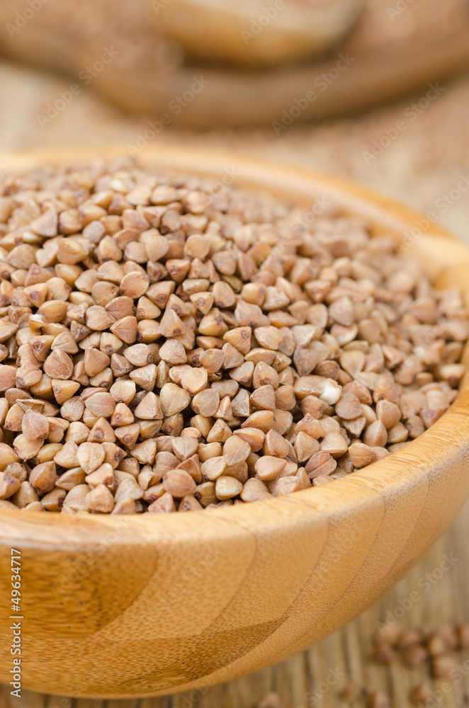 Buckwheat in a wooden bowl, closeup Buckwheat in a wooden bowl, closeup