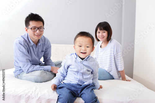 A happy family sitting on white bed