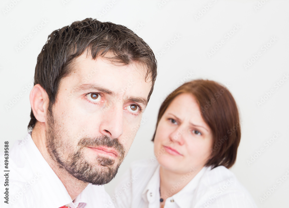 Portrait of upset young couple sitting seperately in the bedroom Portrait of upset young couple sitting seperately in the bedroom