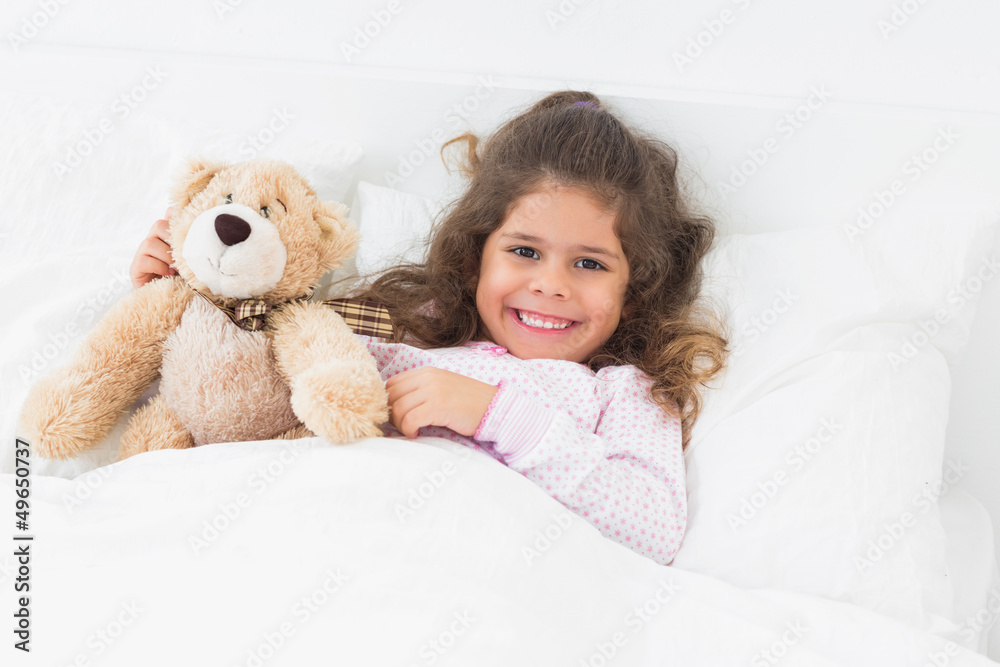 Little girl in bed with teddy bear