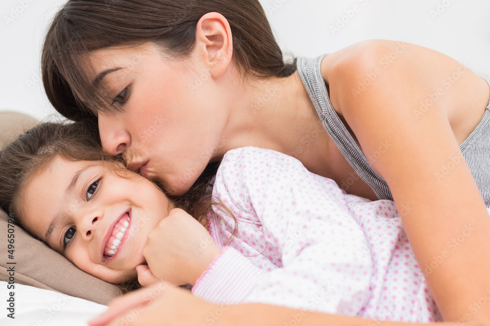 Mother kissing happy daughter on the cheek Mother kissing happy daughter on the cheek