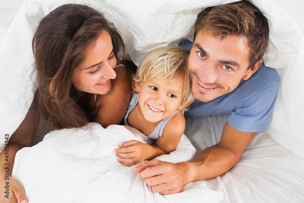 Family lying in the duvet on the bed