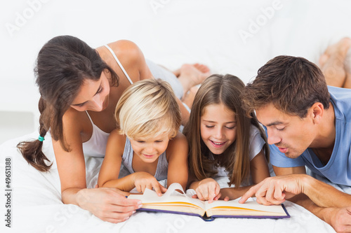 Family reading a book on the bed