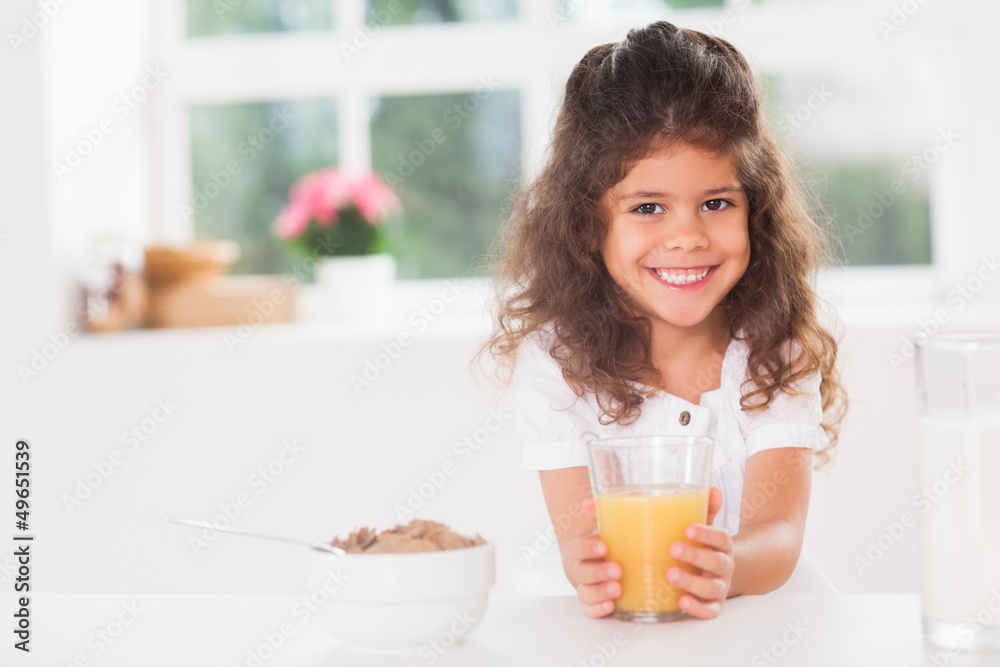Little girl smiling with her orange juice in hand Little girl smiling with her orange juice in hand