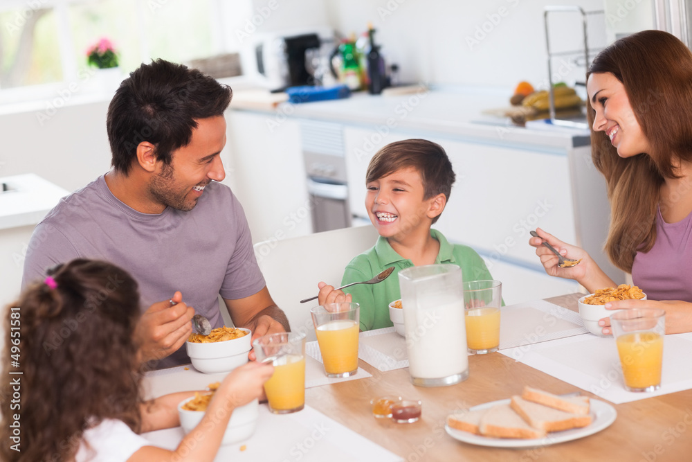 Family laughing around breakfast Family laughing around breakfast