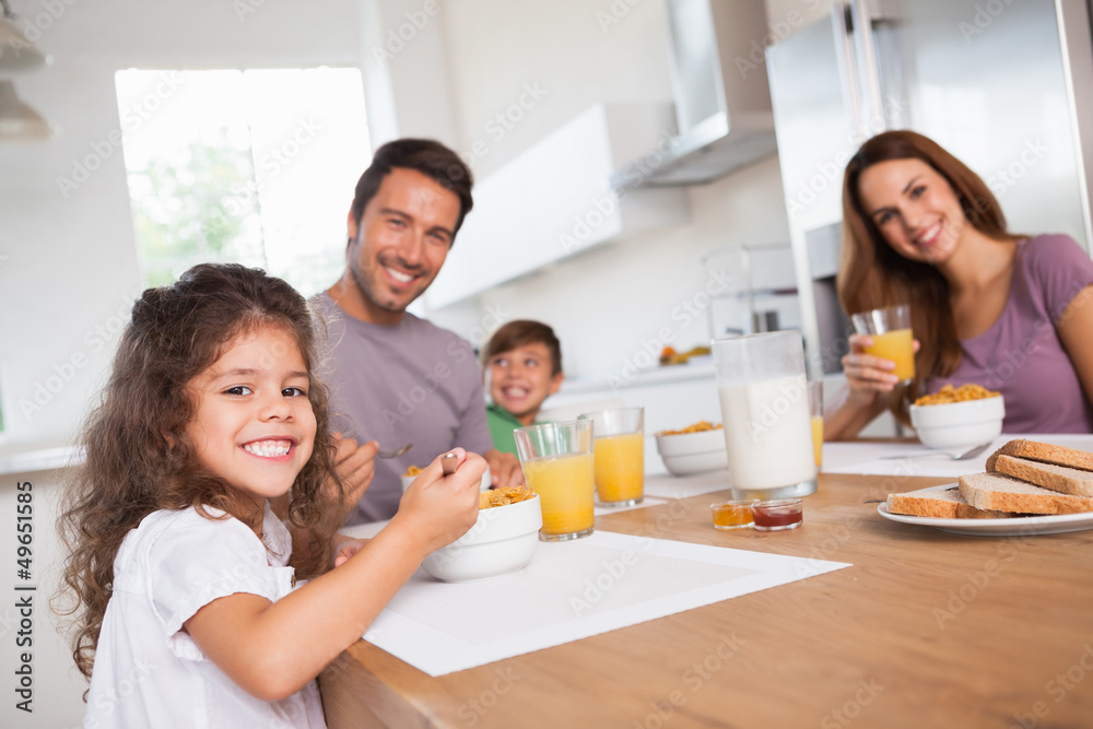 Family smiling at the camera at breakfast