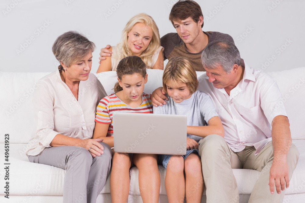 Family looking at laptop on couch Family looking at laptop on couch
