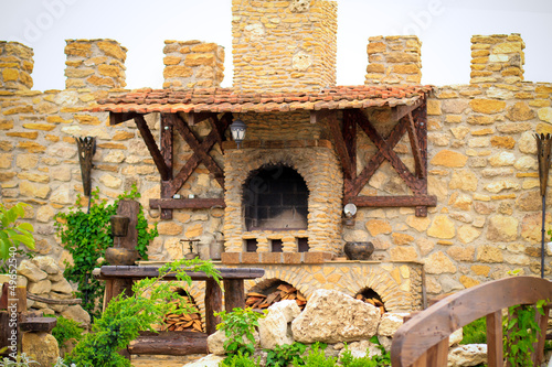 Smoky antique brick oven outdoor with firewood, dishes