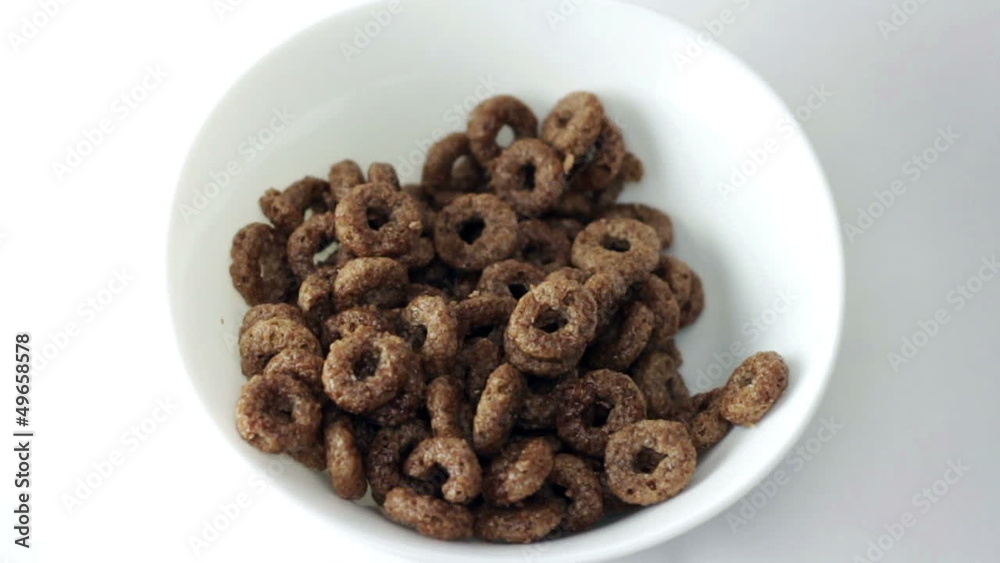 chocolate corn rings falling into white bowl chocolate corn rings falling into white bowl