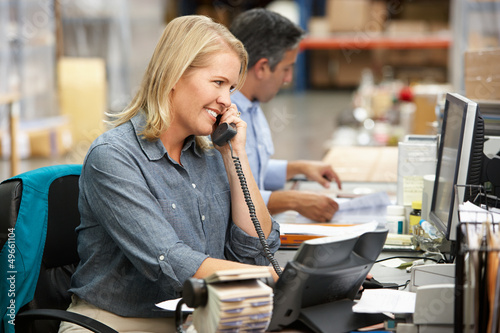Tablou pe pânză Businesswoman Working At Desk In Warehouse