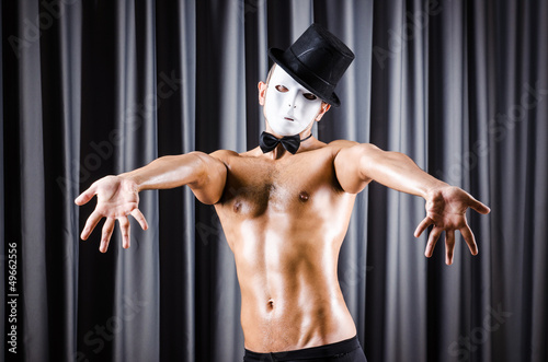 Muscular actor with mask against curtain
