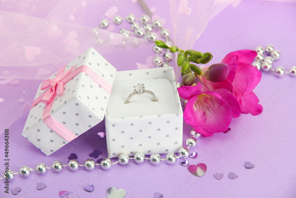 Beautiful box with wedding ring and flower on purple background Beautiful box with wedding ring and flower on purple background