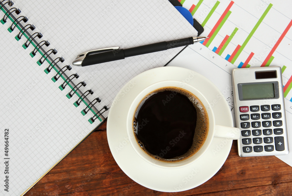 Cup of coffee on worktable covered with documents close up Cup of coffee on worktable covered with documents close up
