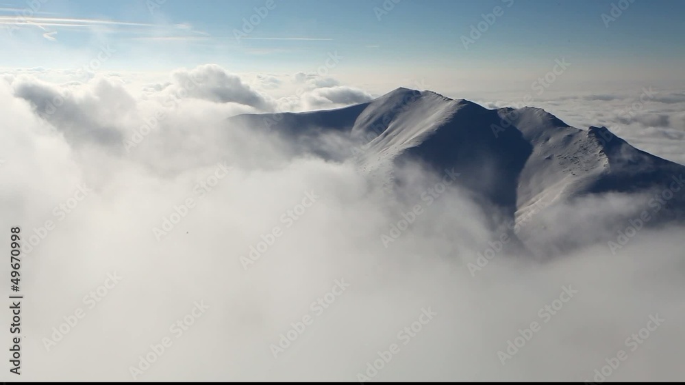 Big mountain over clouds form in a valley - time lapse video