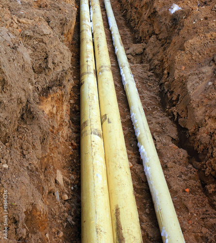 Three pipes in the trench in the ground photo