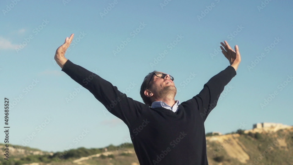 Successful young man raising arms to the sky Successful young man raising arms to the sky