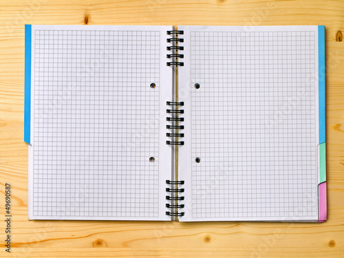 open notebook with graph paper on wood surface