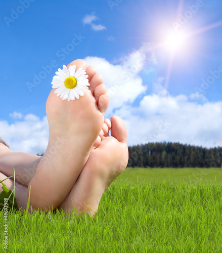 Naked feet in grass with daisy