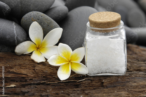 frangipani and stones with salt in glass on driftwood texture