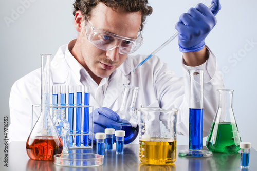 chemist working at a lab bench with various solutions
