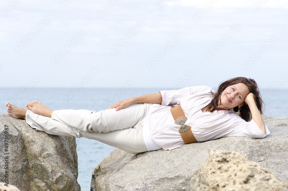 Friendly attractive mature woman lying at ocean