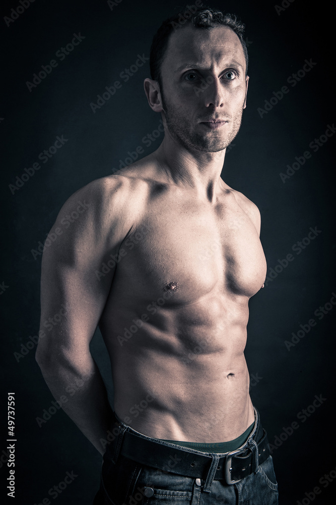 Fototapeta premium Confident young man shirtless portrait against black background.