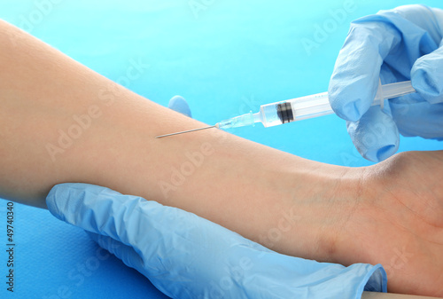 Doctor holding syringe with a vaccine in the patient hand,