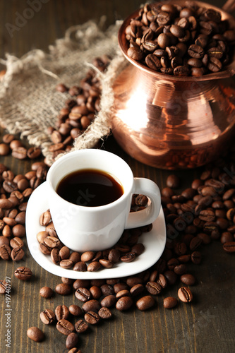 Cup of coffee and pot on wooden background