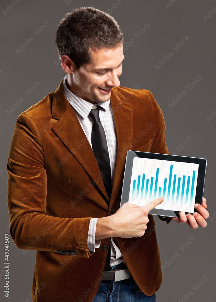 Young businessman touching a tablet screen with graphics.