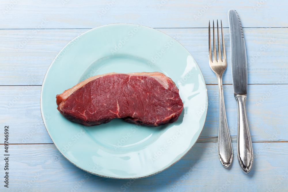 rohes Steak auf einem blauen Teller rohes Steak auf einem blauen Teller