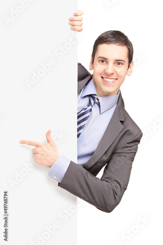 A young businessman in suit pointing on a blank panel